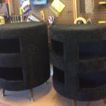 Two black carpeted cat condos side by side on a work bench